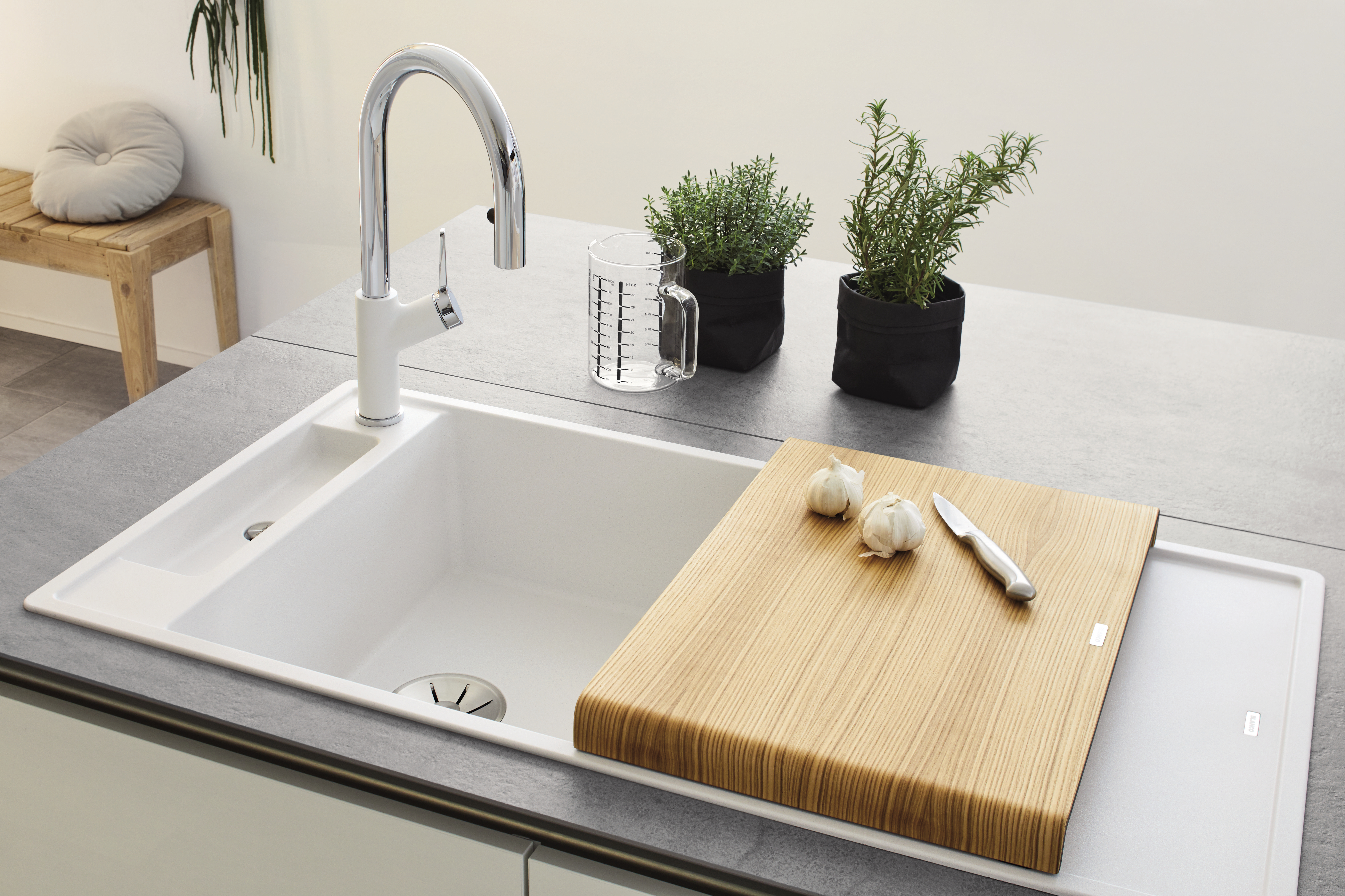 Garlic lying on a chopping board, next to a white BLANCO AXIA sink