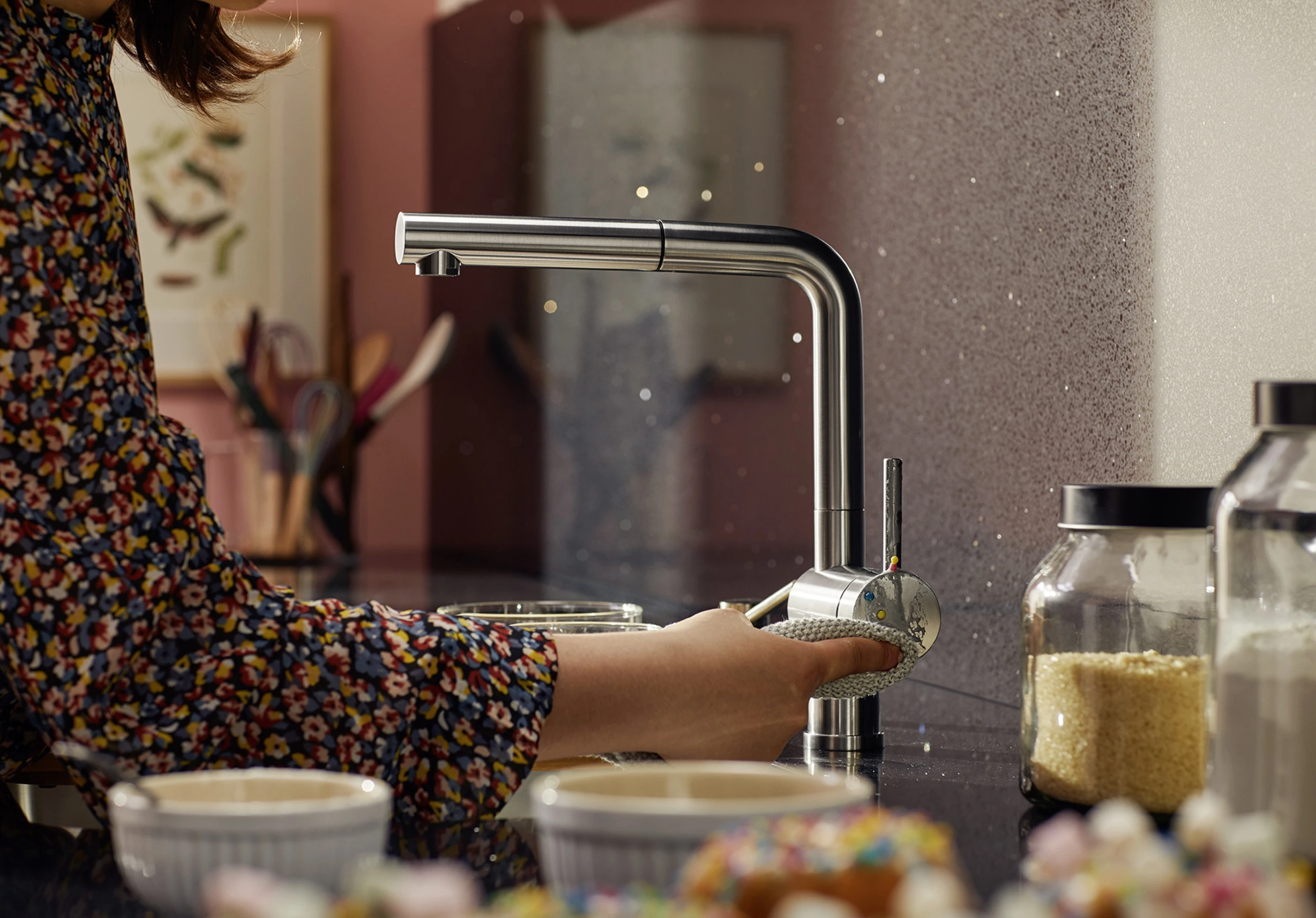 A housewife cleans the mixer tap with a microfibre cloth