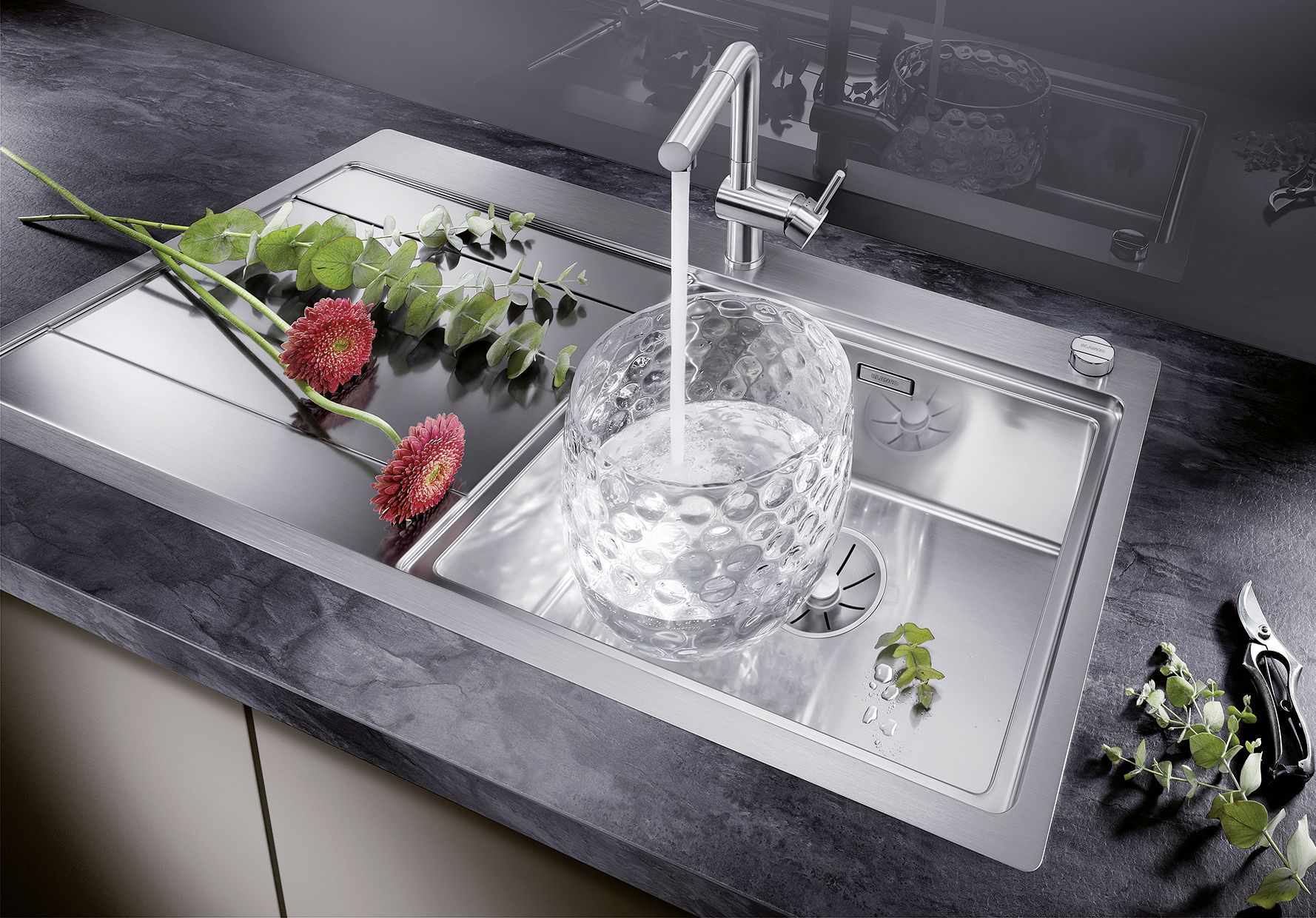 flowers on the stainless steel sink and a vase fullfilled with the water