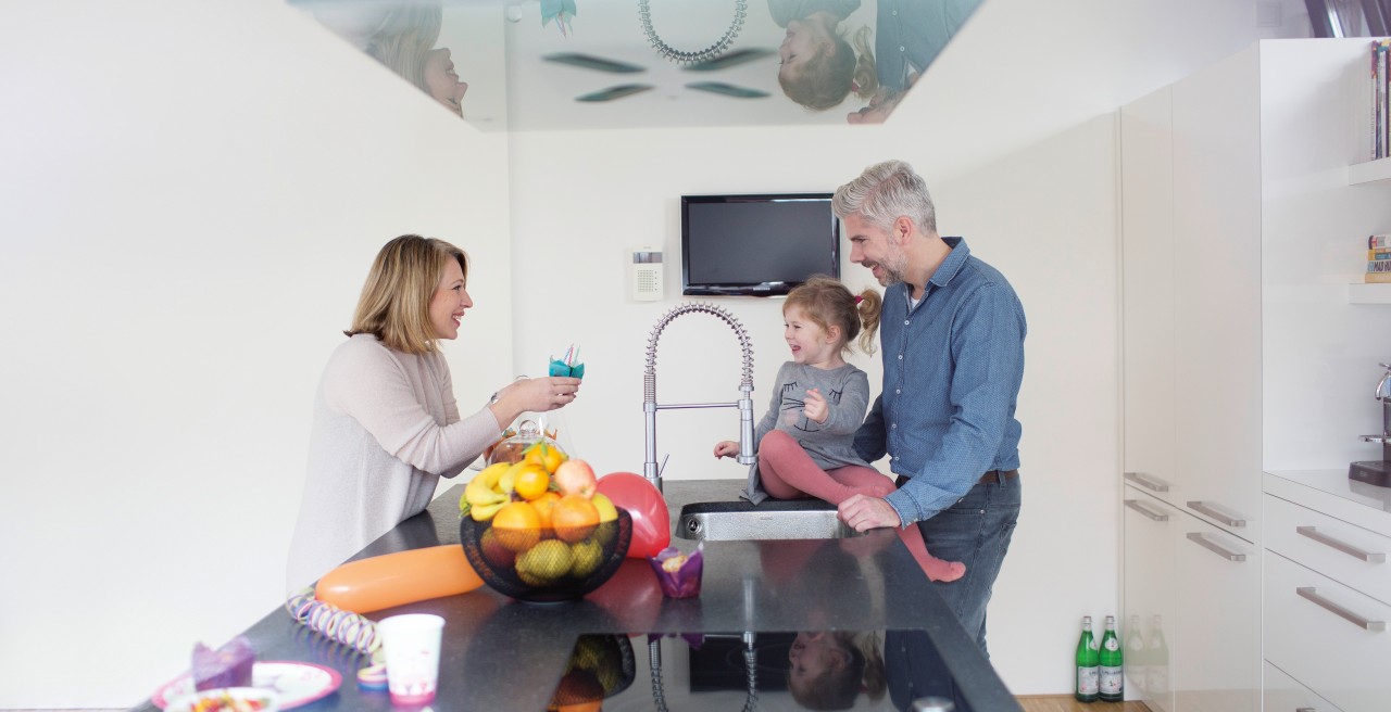 A little girl sits on the sink and fools around with her parents
