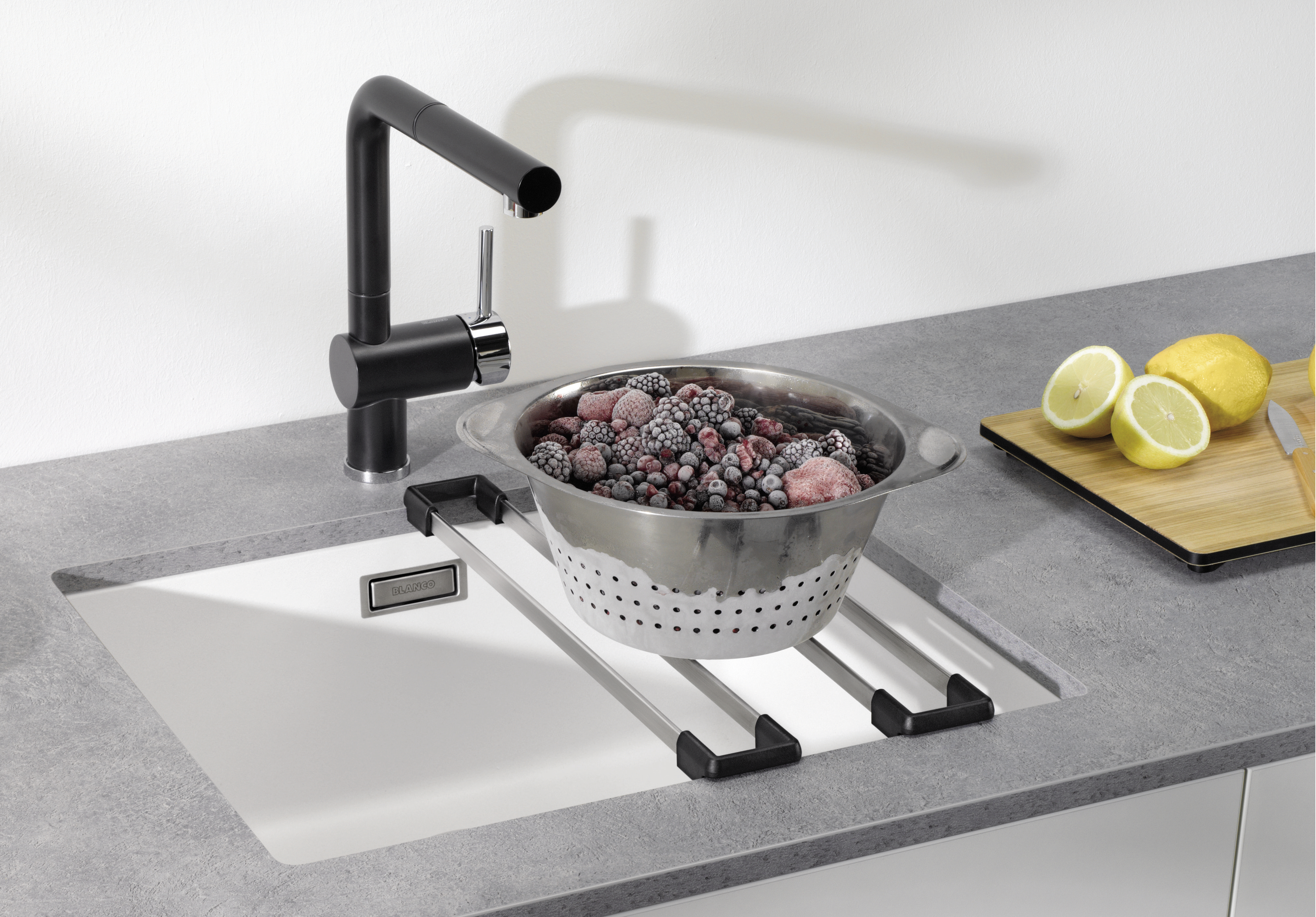 Frozen berries in a stainless steel bowl on a Blanco sink